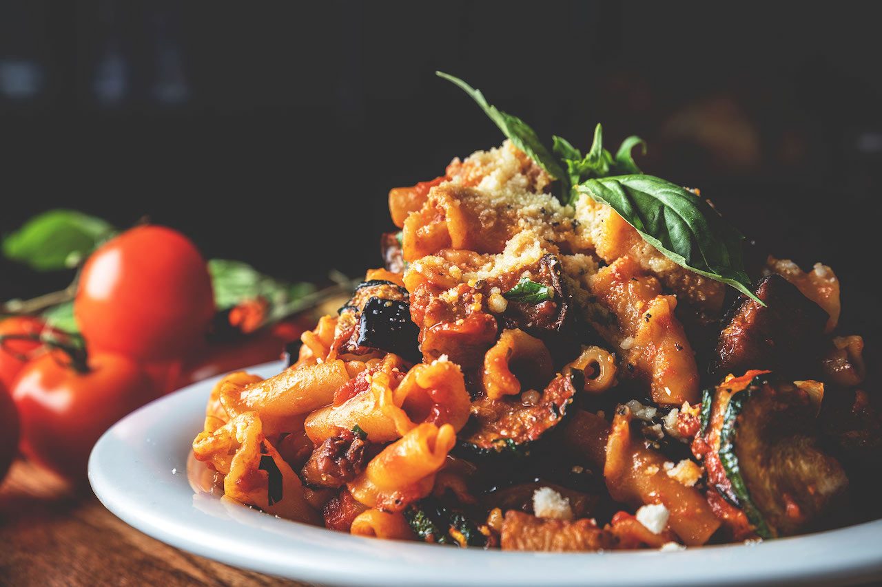 A tempting plate of pasta with eggplant, showcasing al dente pasta tossed with sautéed eggplant slices, garlic, olive oil, and herbs, garnished with grated cheese and fresh parsley, offering a delicious and satisfying Italian-inspired dish at Spumoni Gardens.