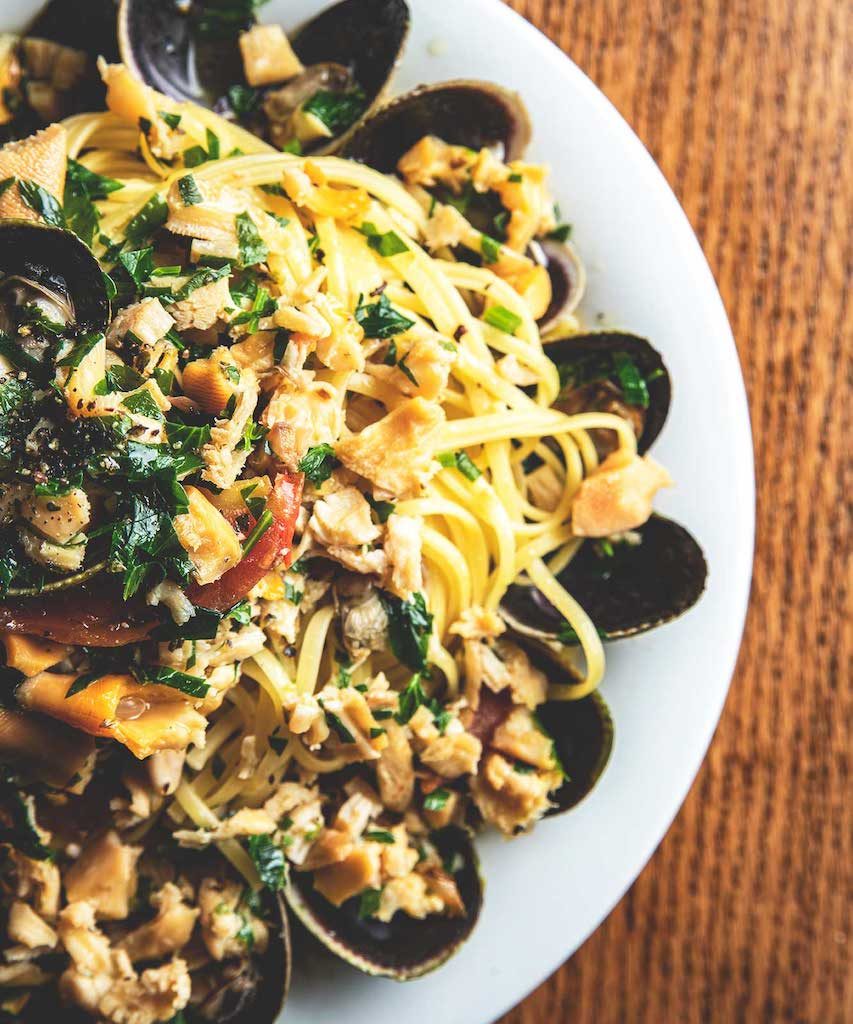 A savory dish of linguine with clams, featuring al dente pasta tossed in a garlic and white wine sauce, mixed with fresh clams in their shells, garnished with chopped parsley, offering a classic and flavorful Italian seafood entrée at Spumoni Gardens.